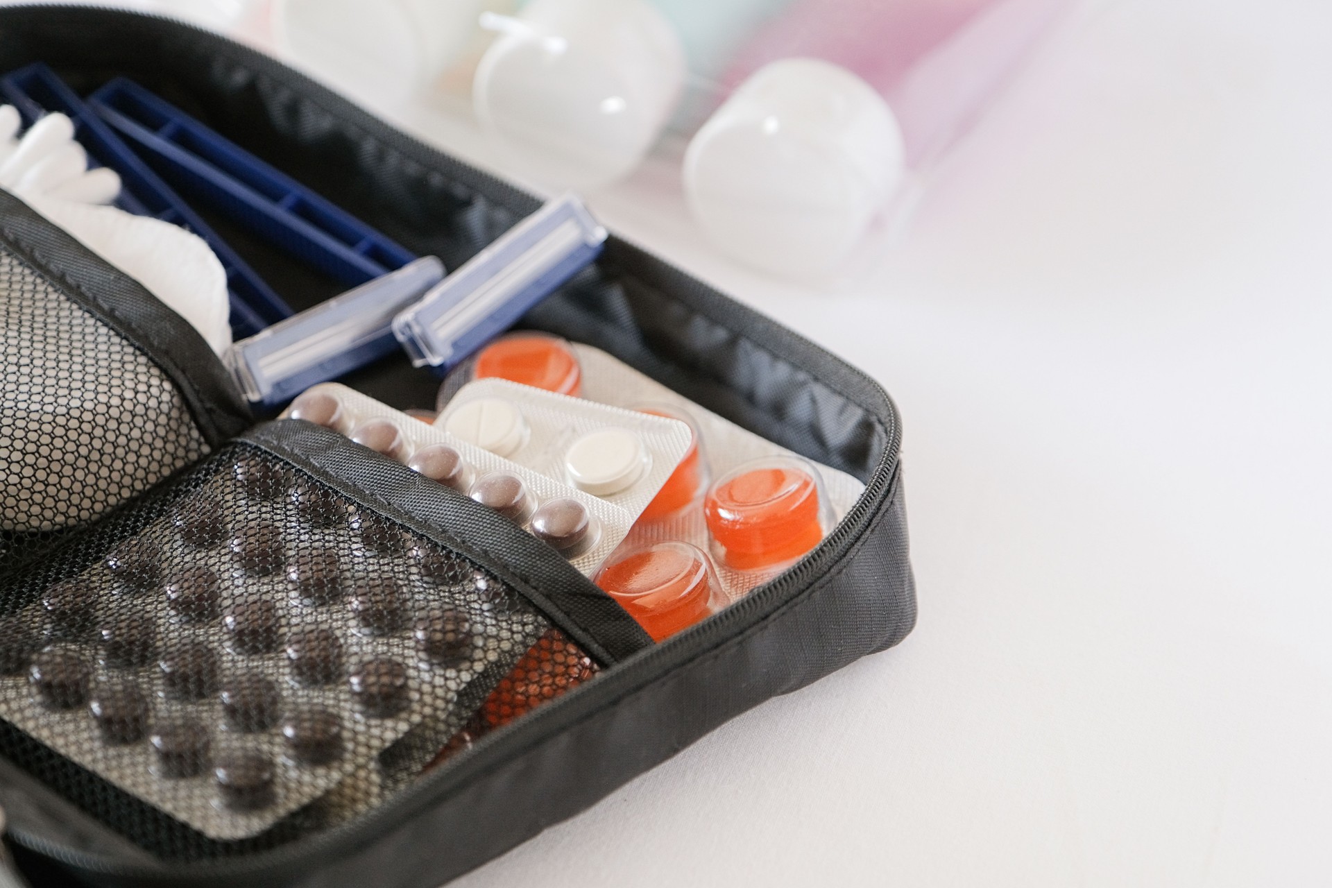 Cosmetic travel kit on the bed with pills and hygiene items for travel