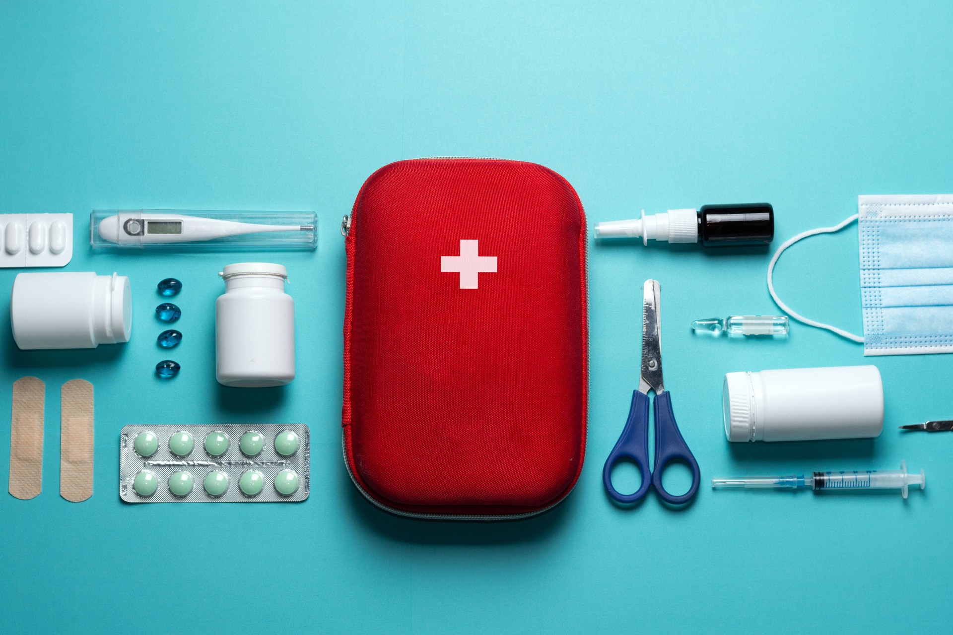 Home first aid kit on a blue background. The elements of the first aid kit are laid out on the table.